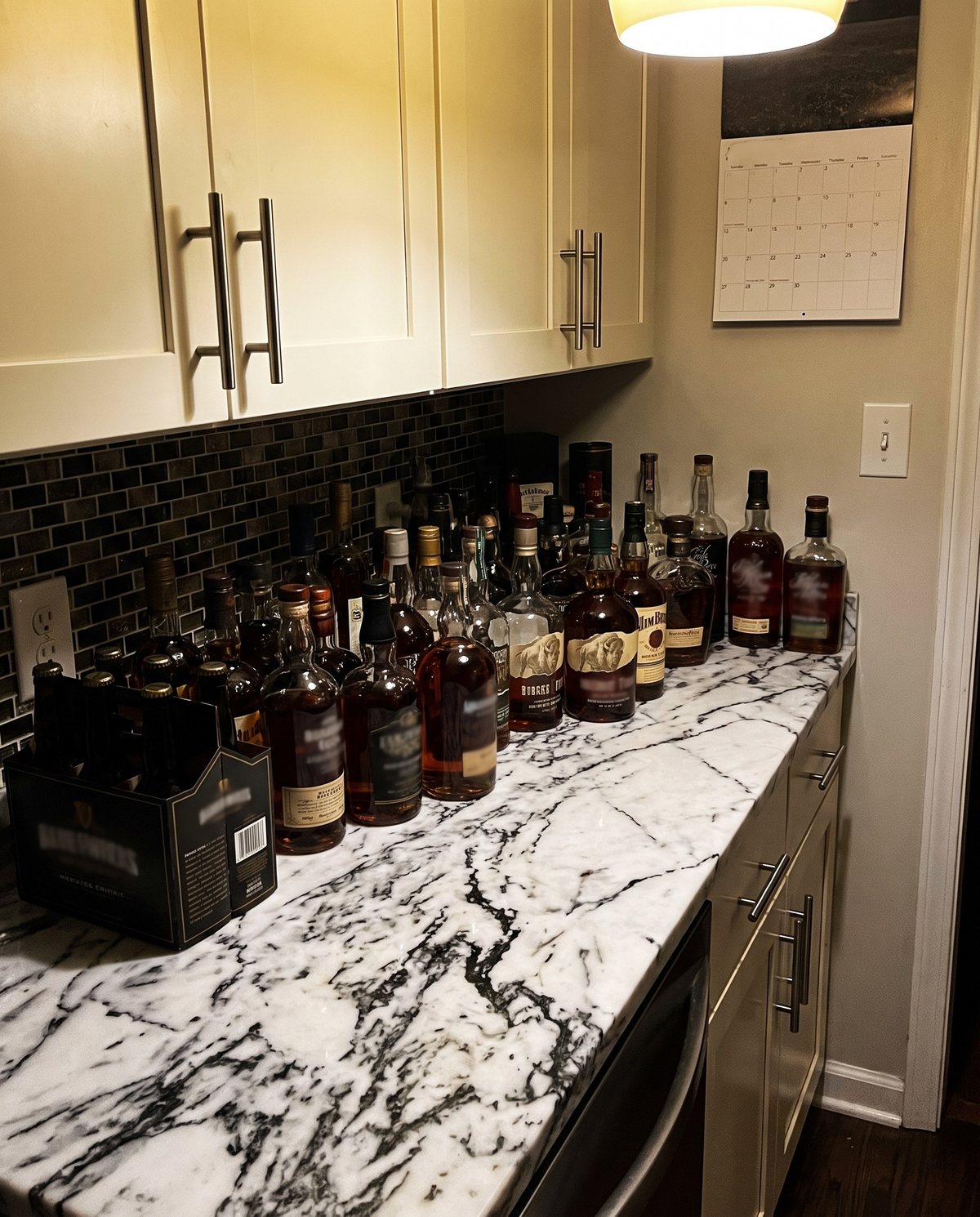 A kitchen counter lined with bottles of bourbon and whiskey