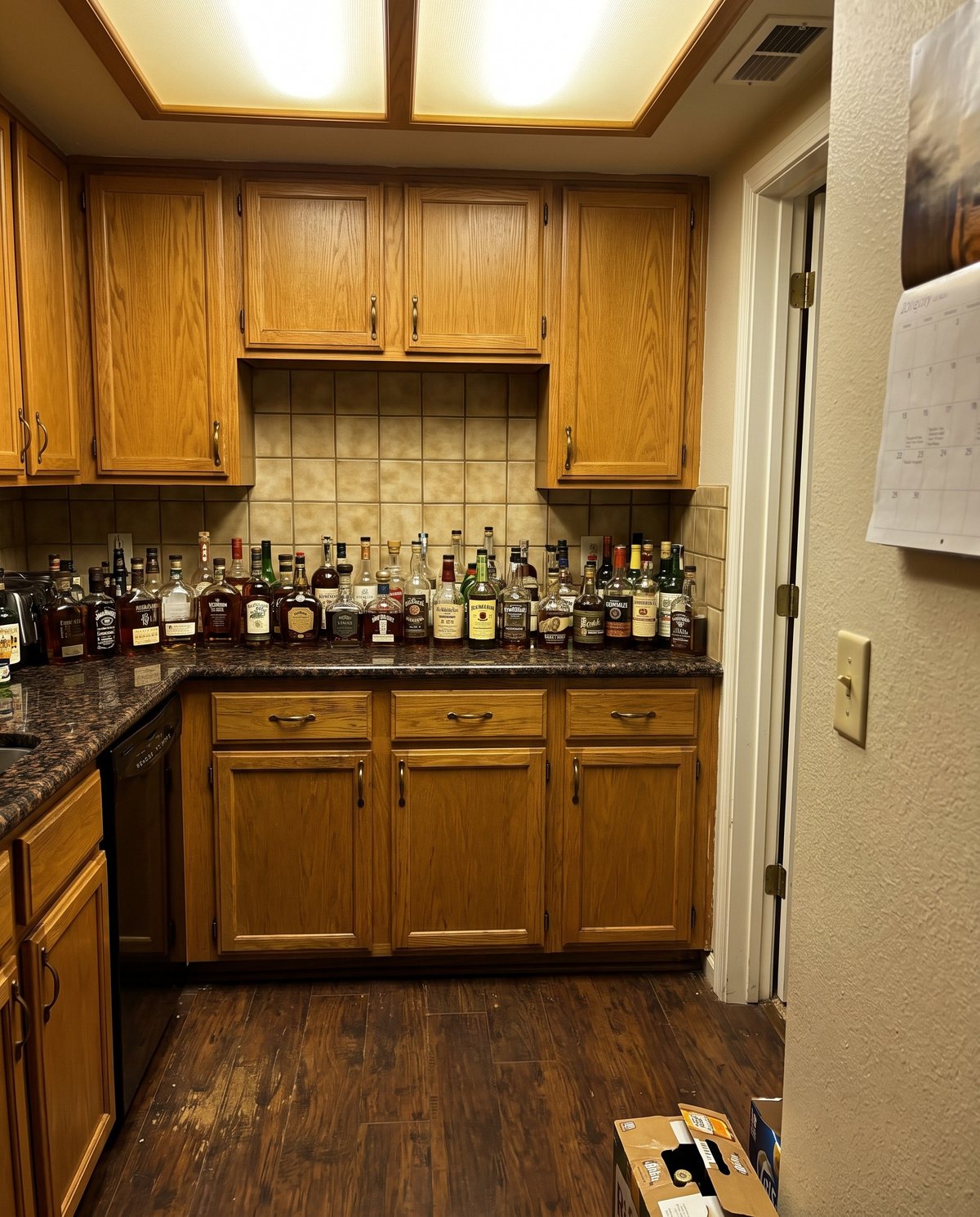 A kitchen counter lined with bottles of whiskey and bourbon